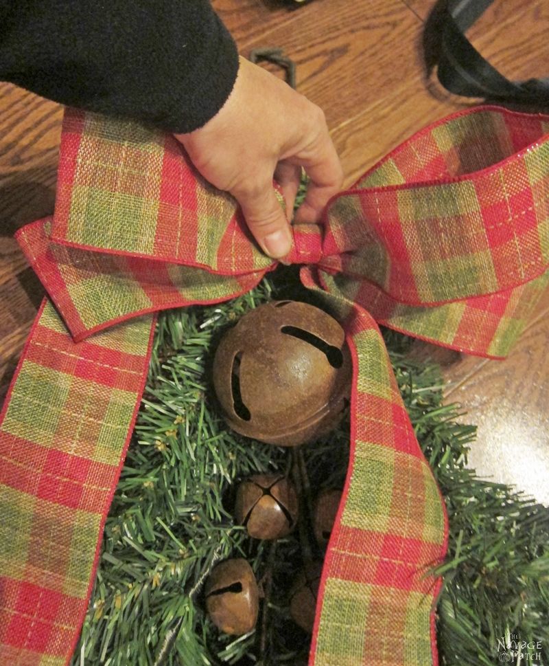 woman attaching a bow to a diy clip-on christmas swag
