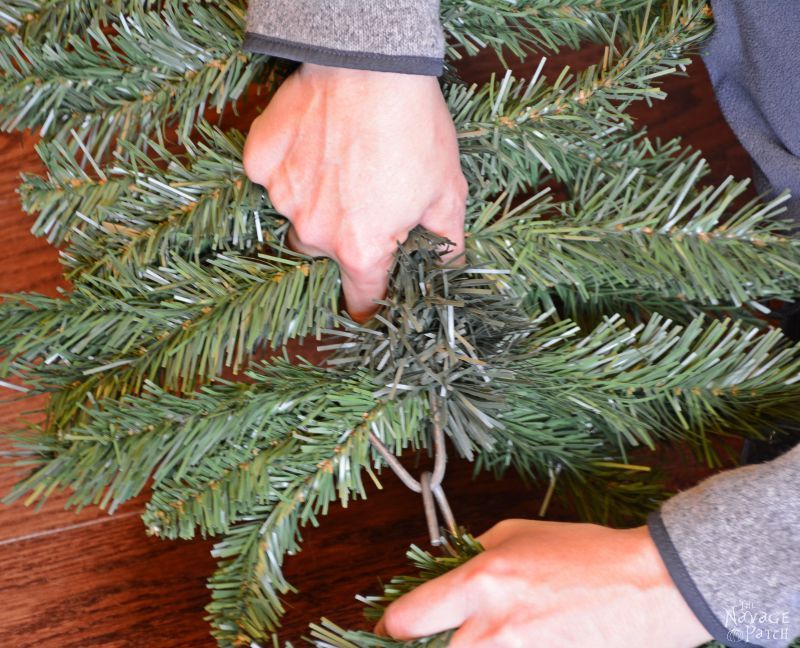 woman connecting two fake christmas tree branches together