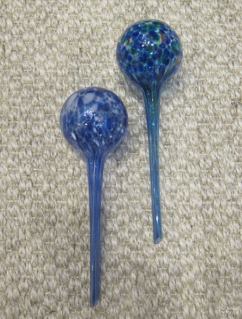 Two glass watering globes on a carpet.