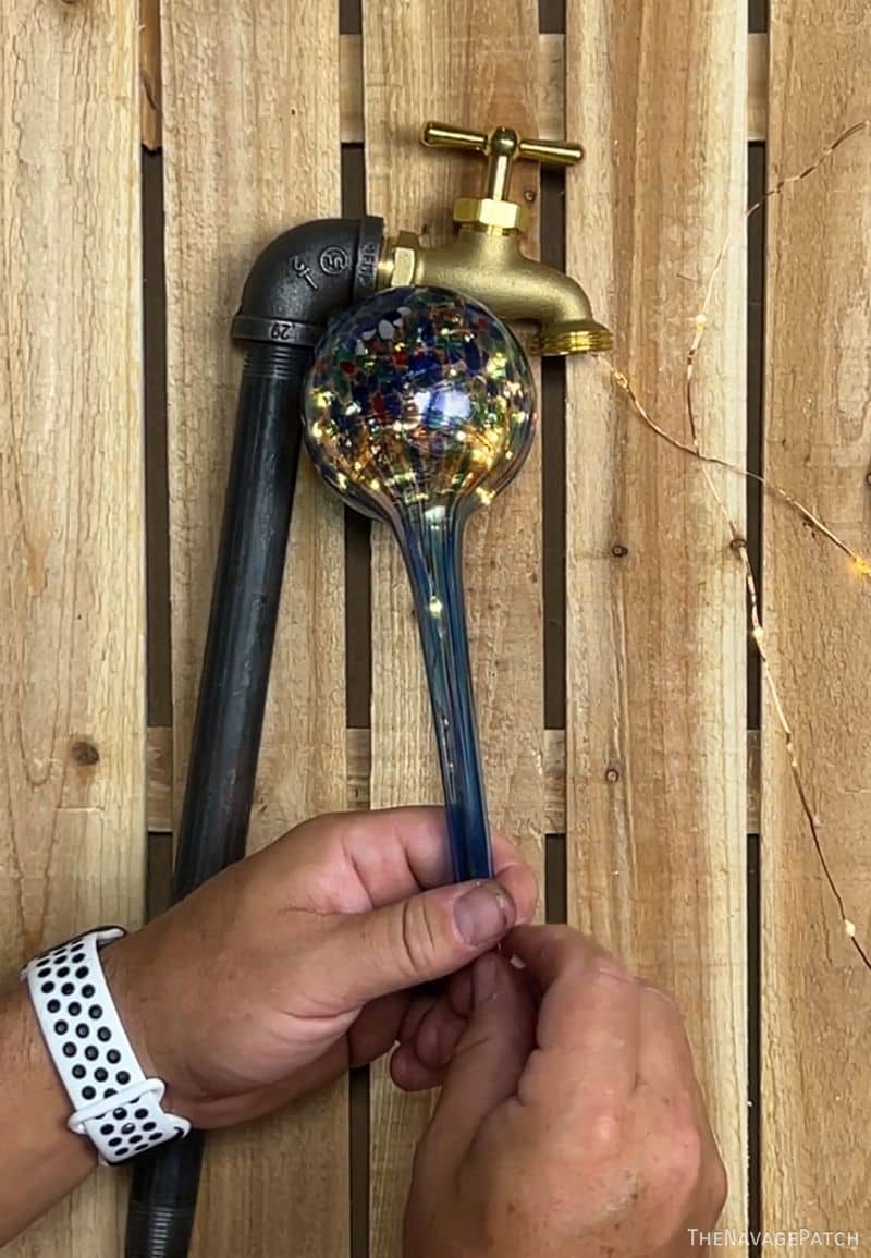 man putting lights into a watering globe