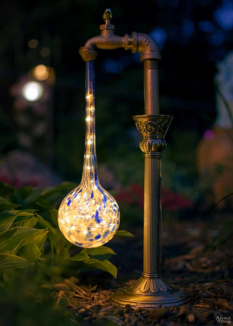 closeup of waterdrop solar light next to a plant at night