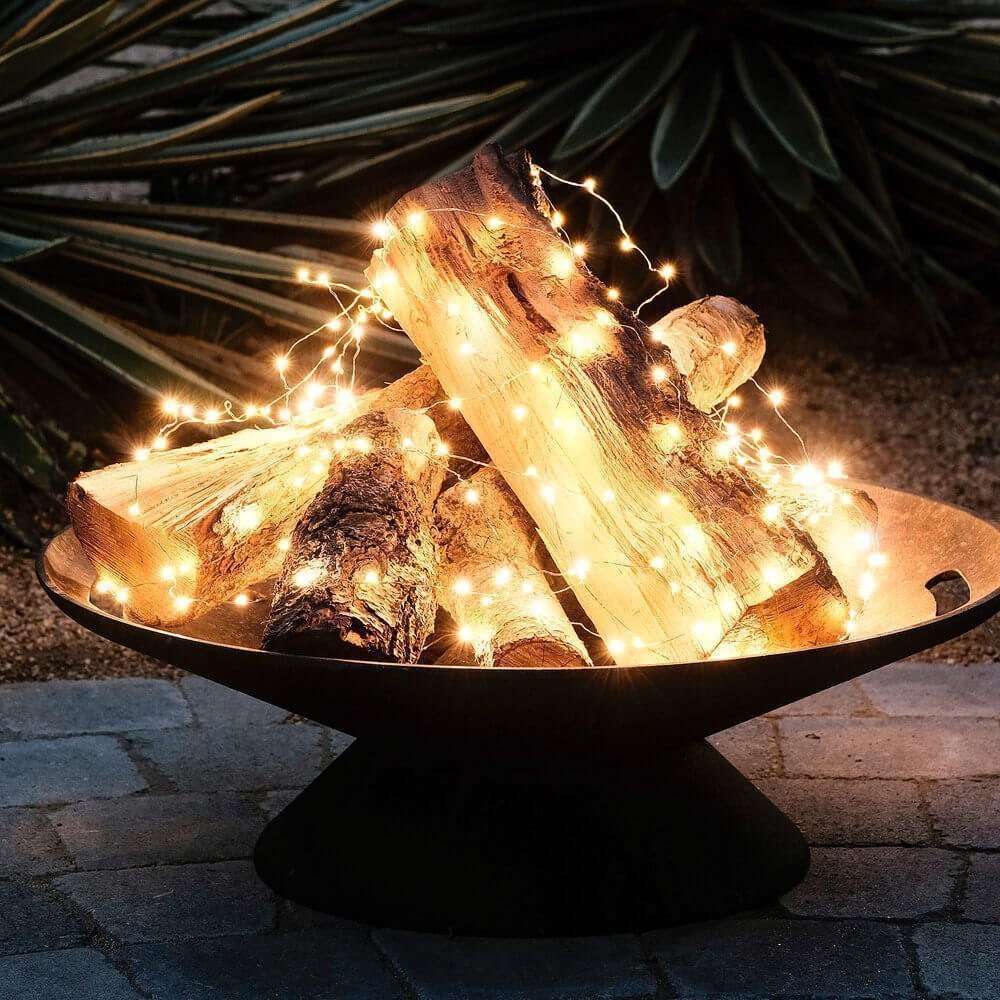 logs in a firepit with starry string lights