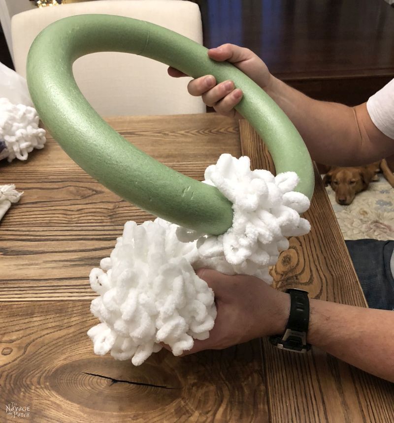 man wrapping loop yarn around wreath form