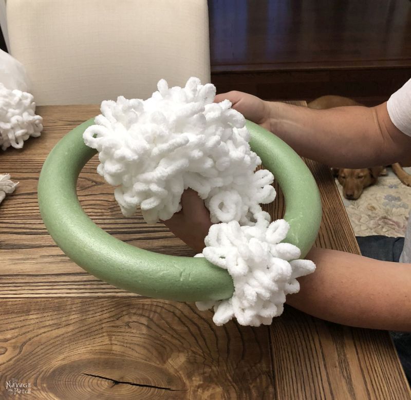 man wrapping loop yarn around foam wreath form