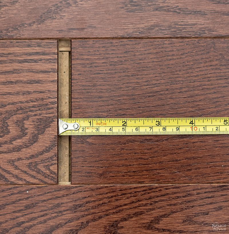 tape measure in a gap between floor boards