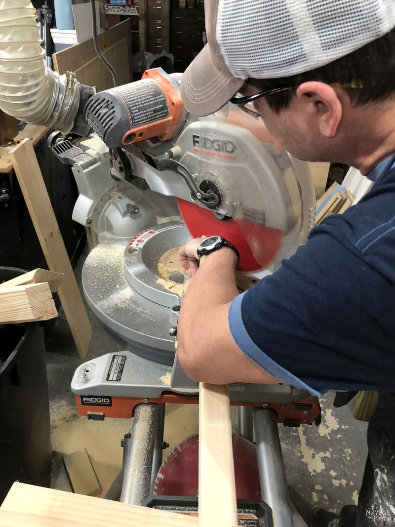 man cutting lumber on a miter saw