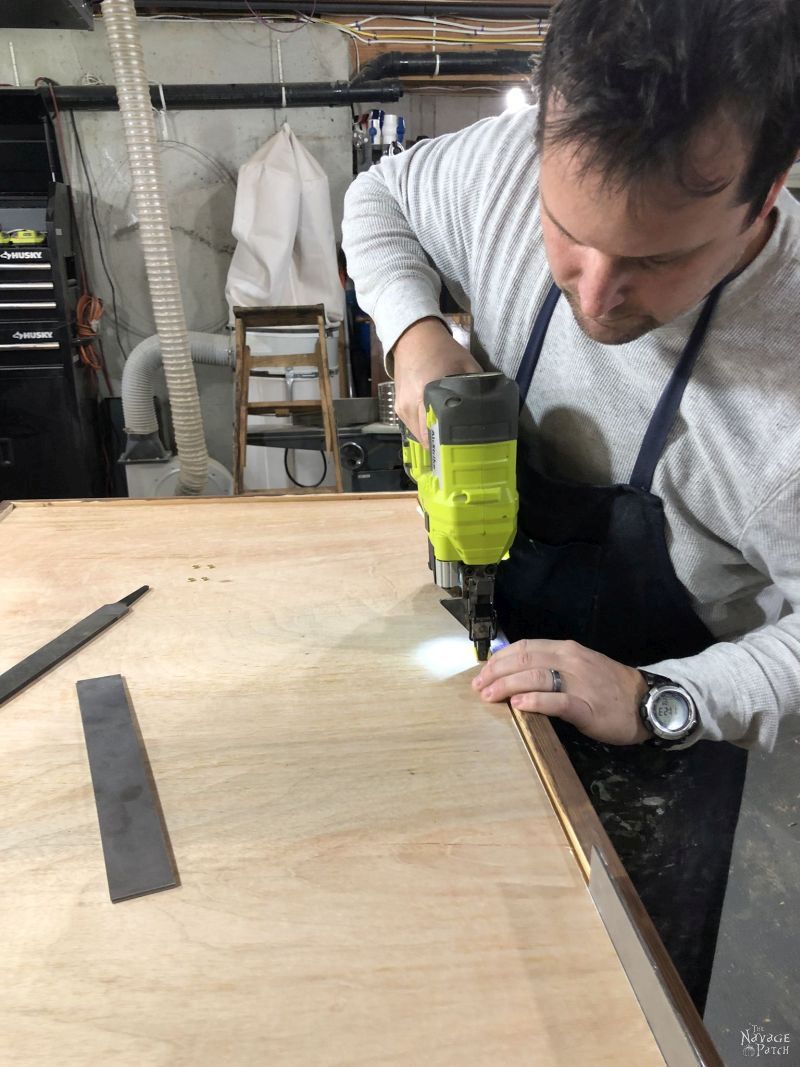 man using a brad nailer to install a frame backing