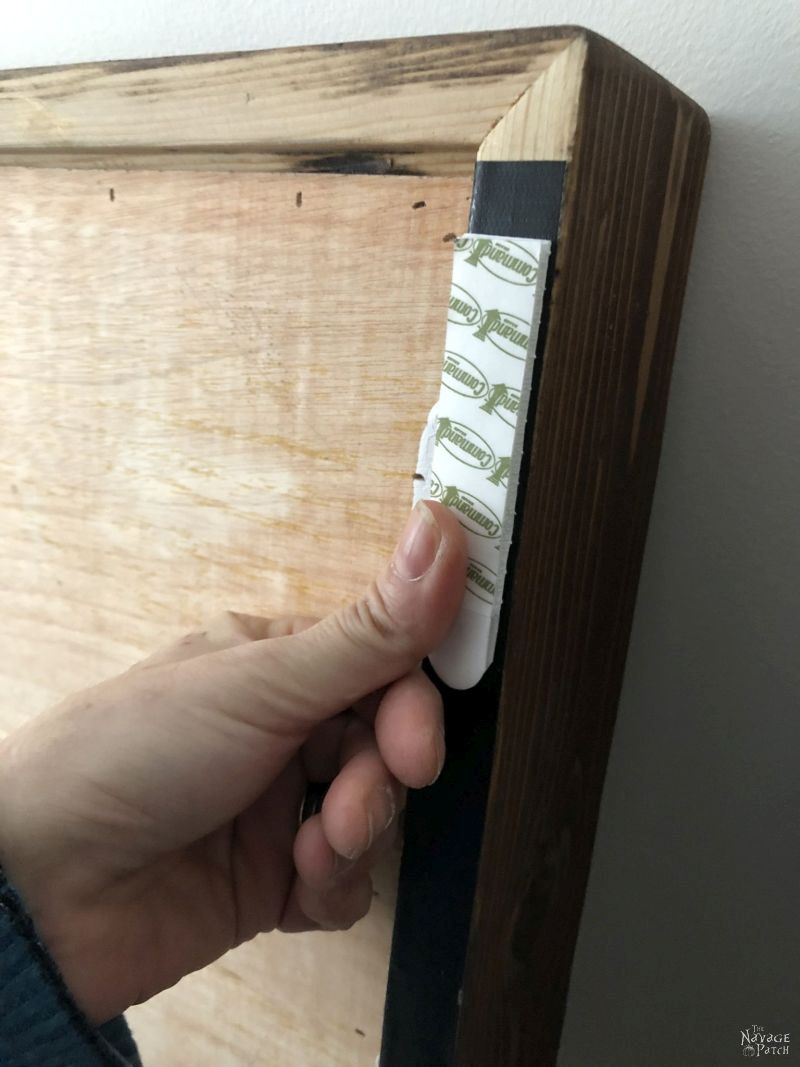 pressing a command strip to the back of a frame