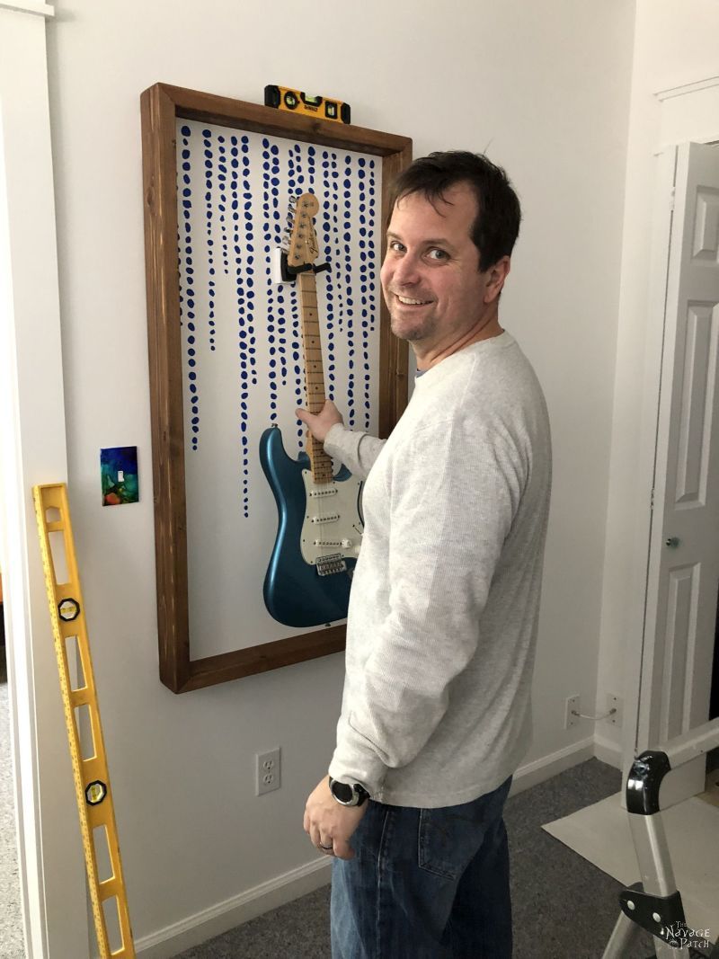 man hanging diy guitar display frame