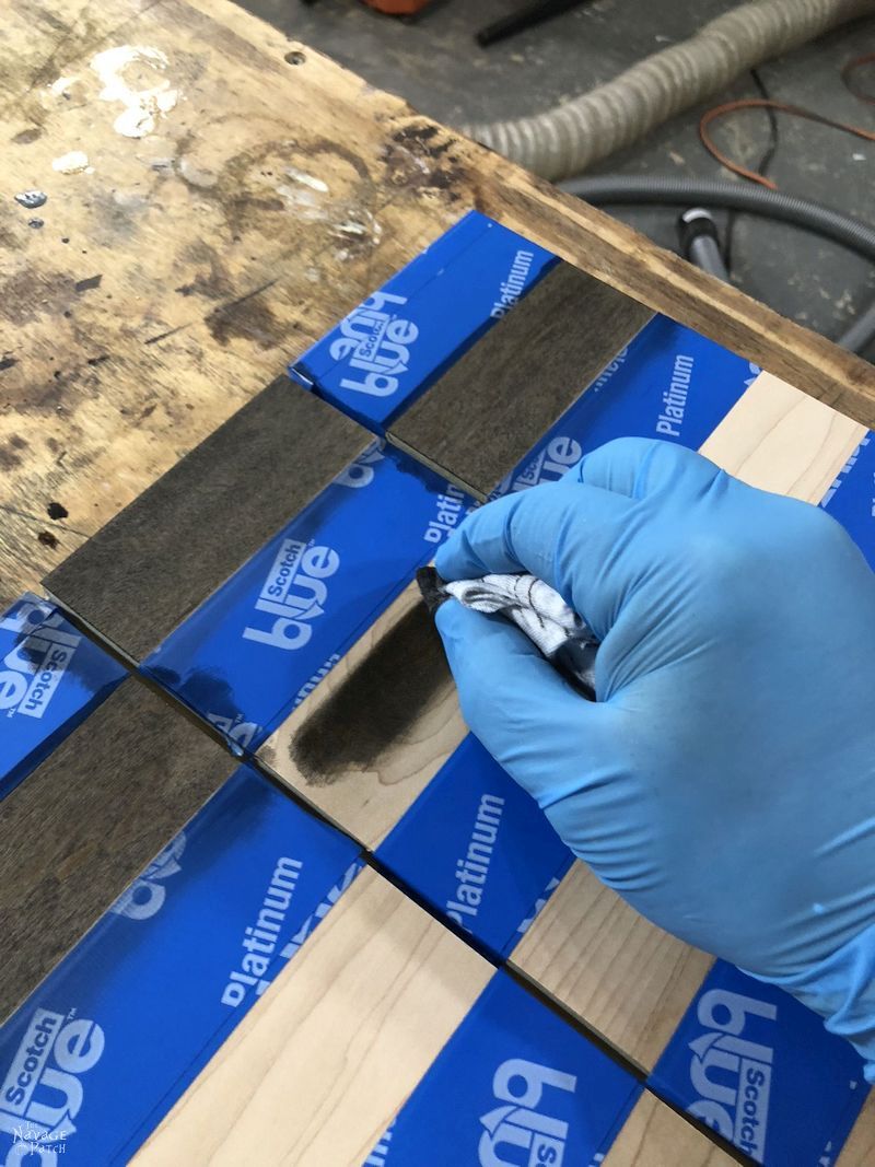gloved hand applying stain to diy vertical chess board