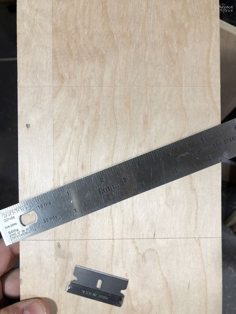 ruler and razor blade on a piece of plywood