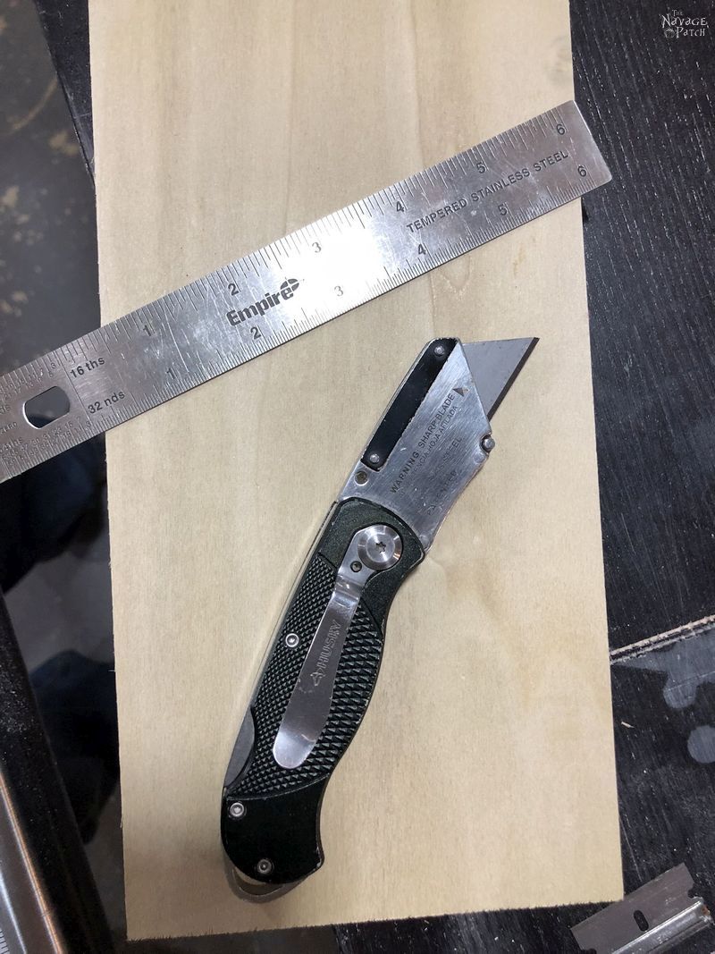 utility knife and ruler on a piece of plywood