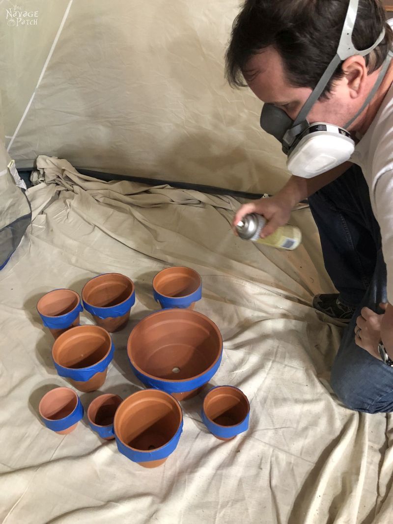 man spraying terra cotta posts with shellac