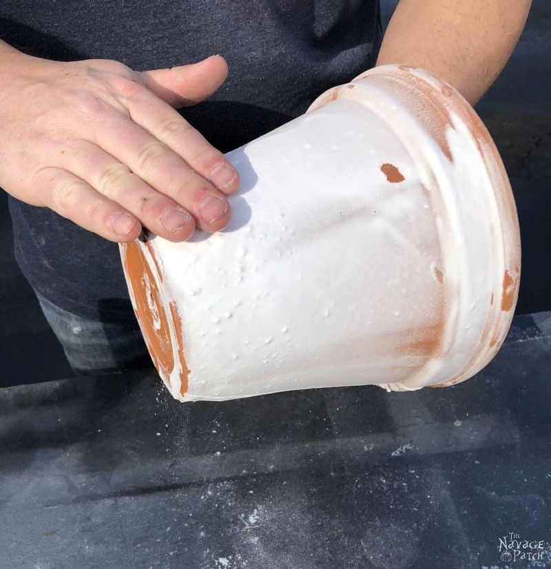 man rubbing excess baking soda from a faux aged terra cotta pot
