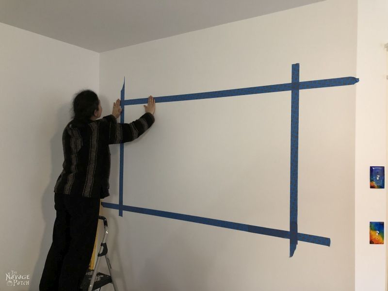 woman putting tape on a wall