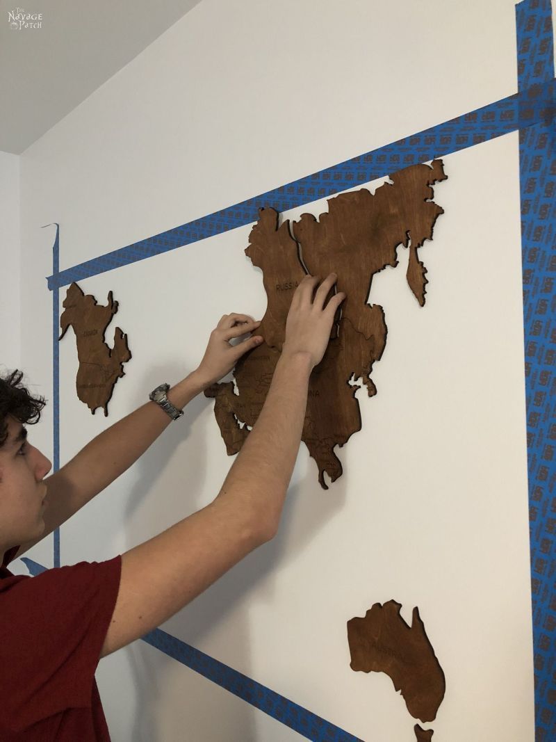 boy sticking wooden country on a wall