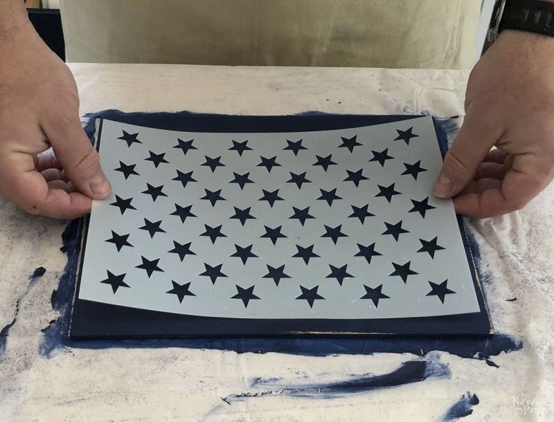 positioning a flag star stencil on a painted piece of wood