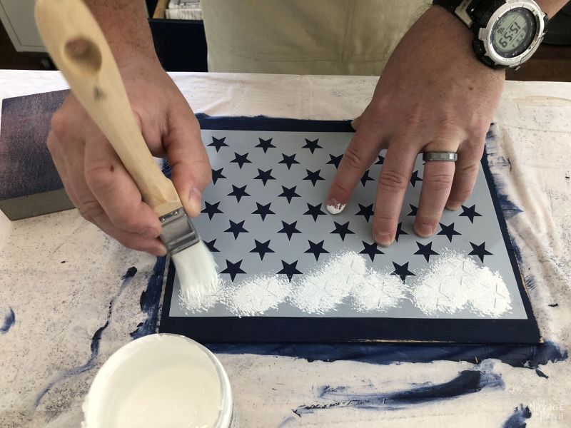 applying white paint to a star stencil