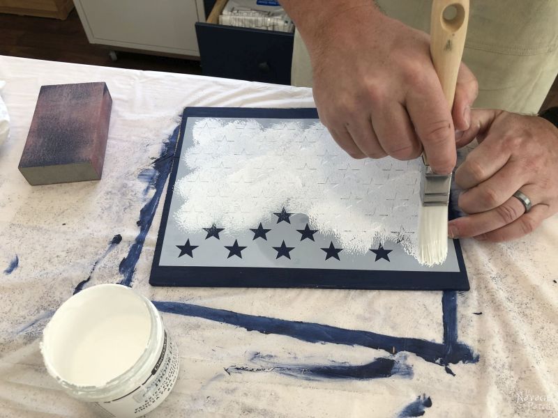 applying white paint to a star stencil