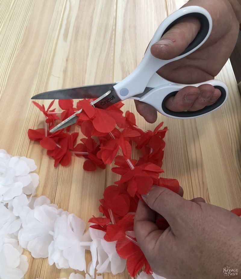 cutting a red lei with scissors