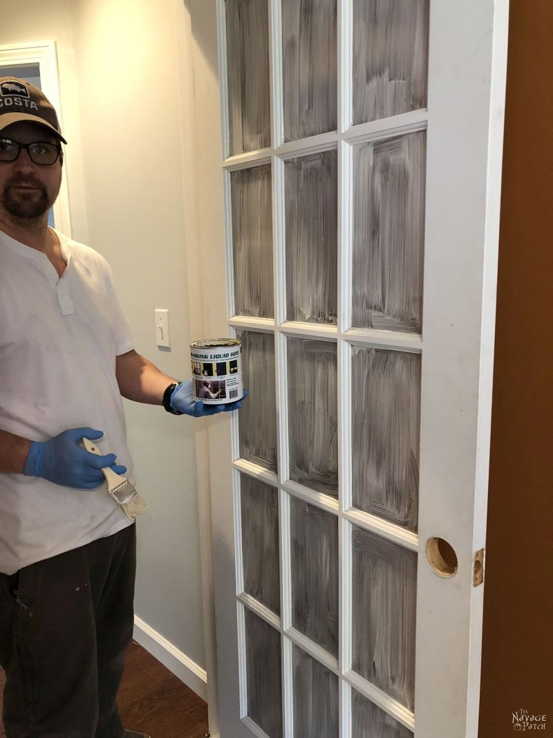 beautiful man holding a can of masking liquid next to a french door that will be painted