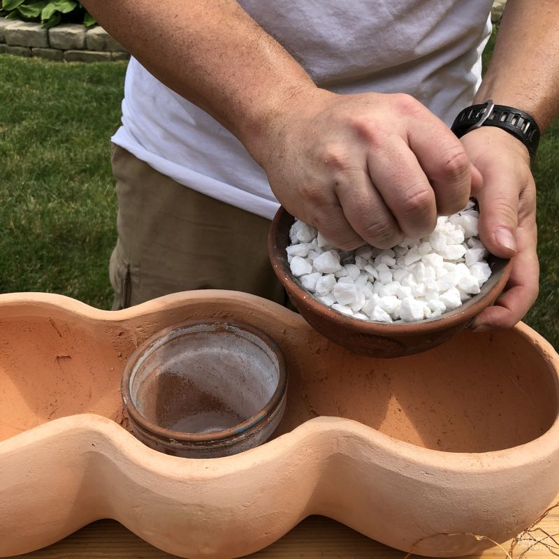 filling a clay pot with crushed stone