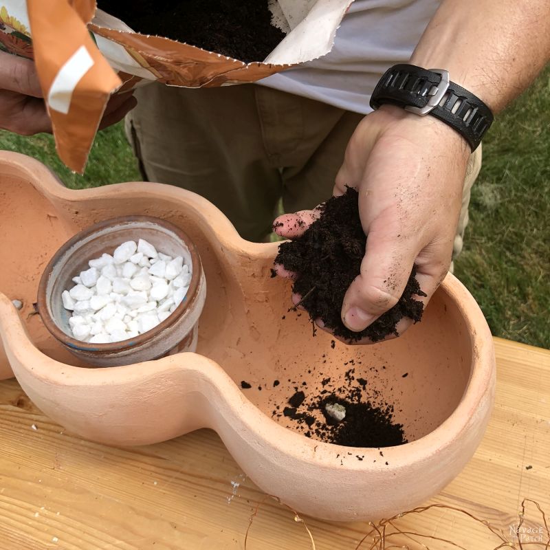 adding soil to a clay pot