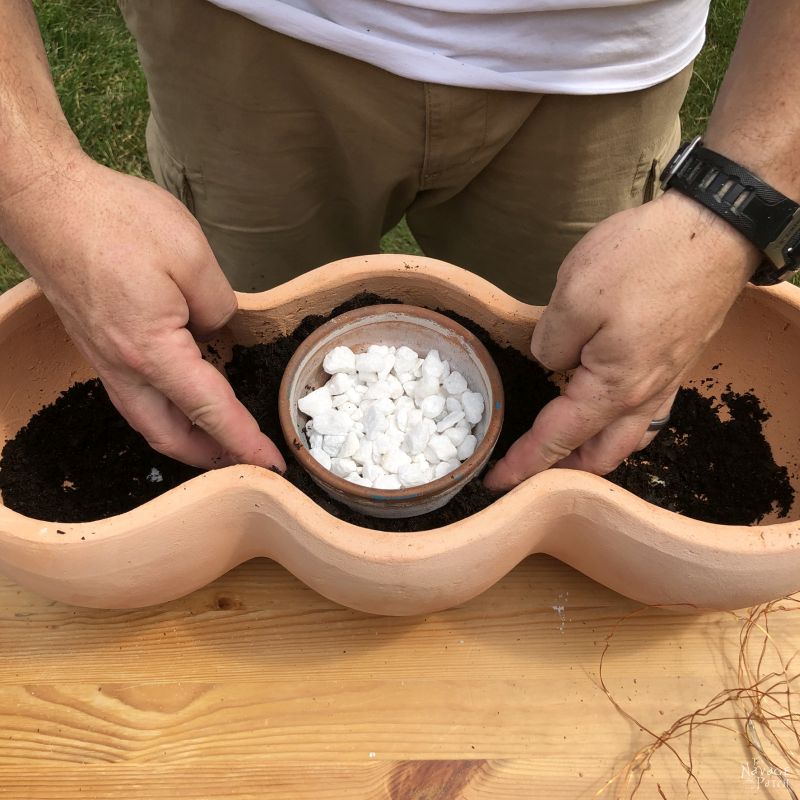 adding soil to a clay pot