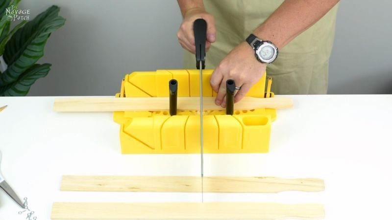 cutting a piece of wood for a magnetic poster hanger on a miter box