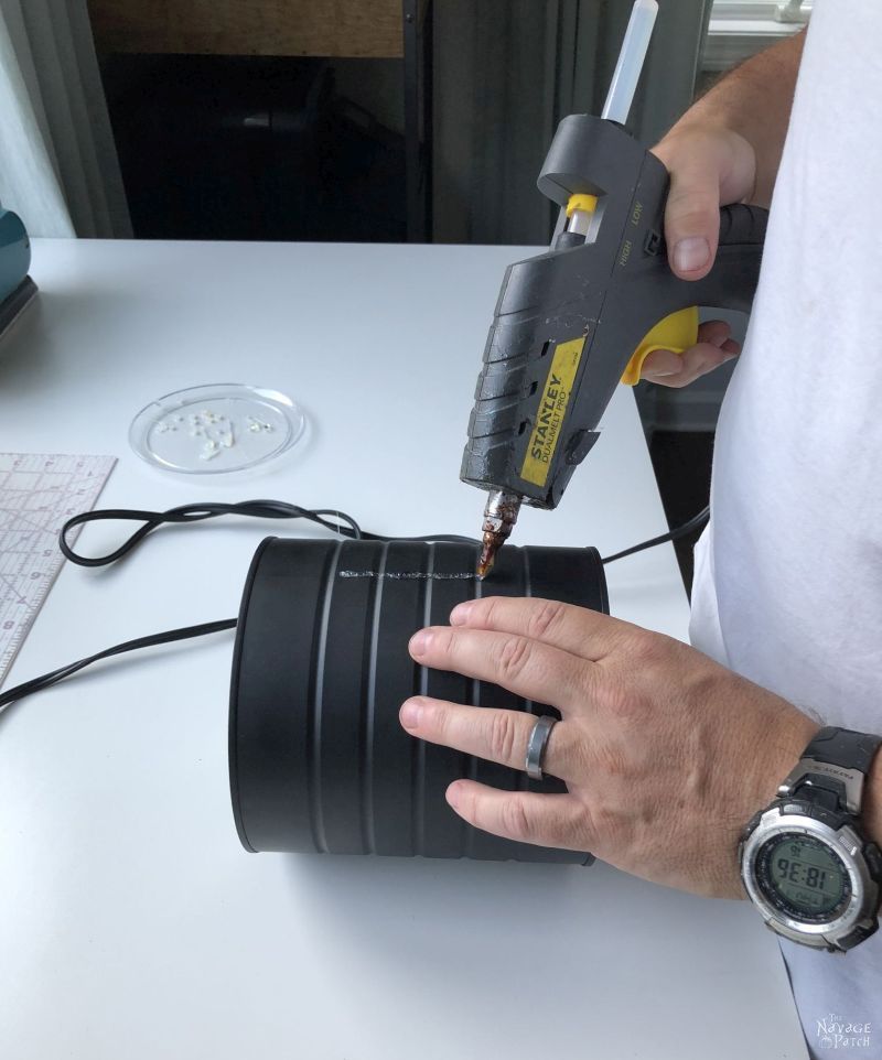 applying hot glue to a painted coffee can