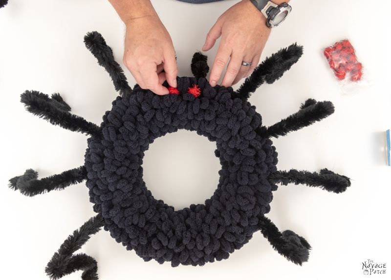 adding pom pom eyes to a spider wreath