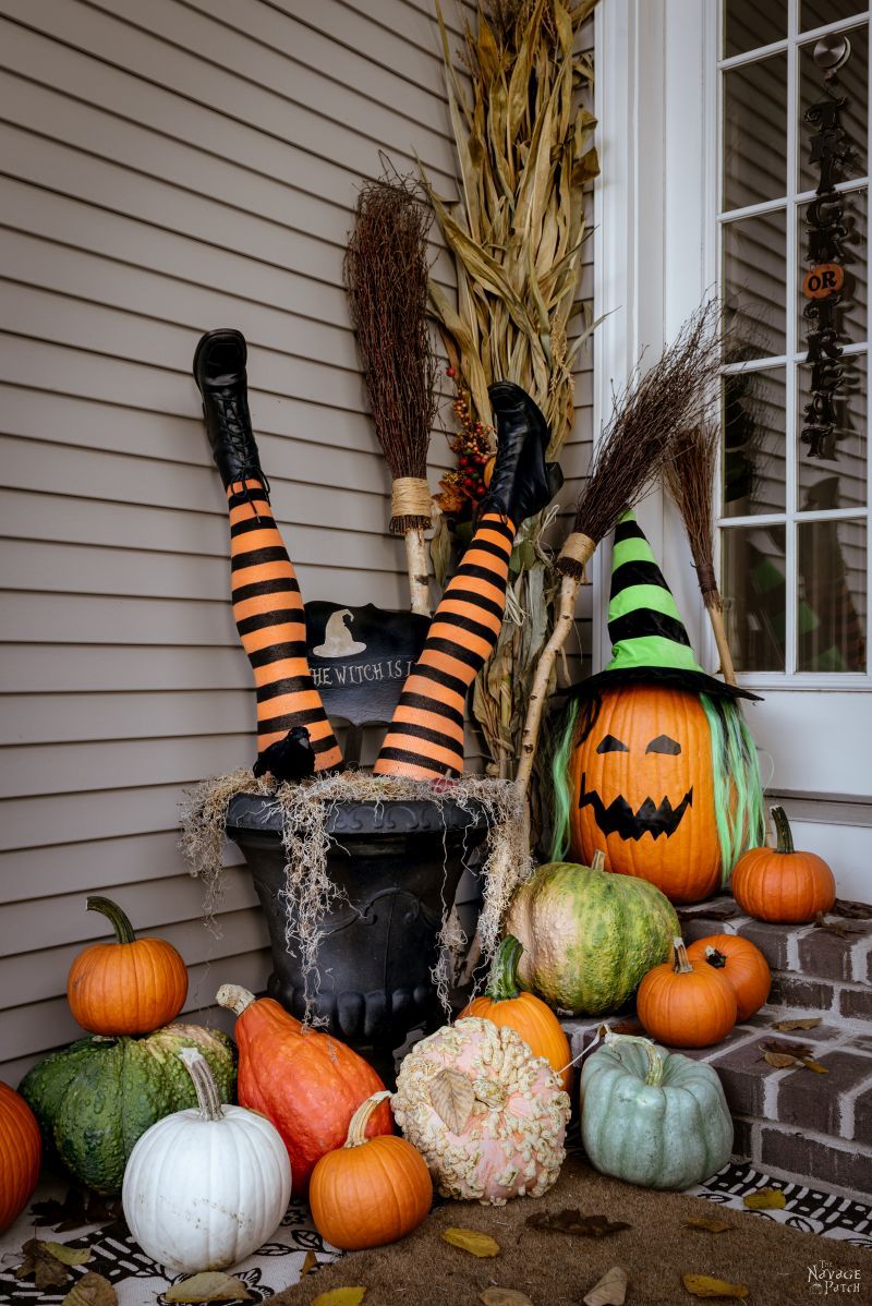 DIY Witch Legs in an urn surrounded by pumpkins on a front porch
