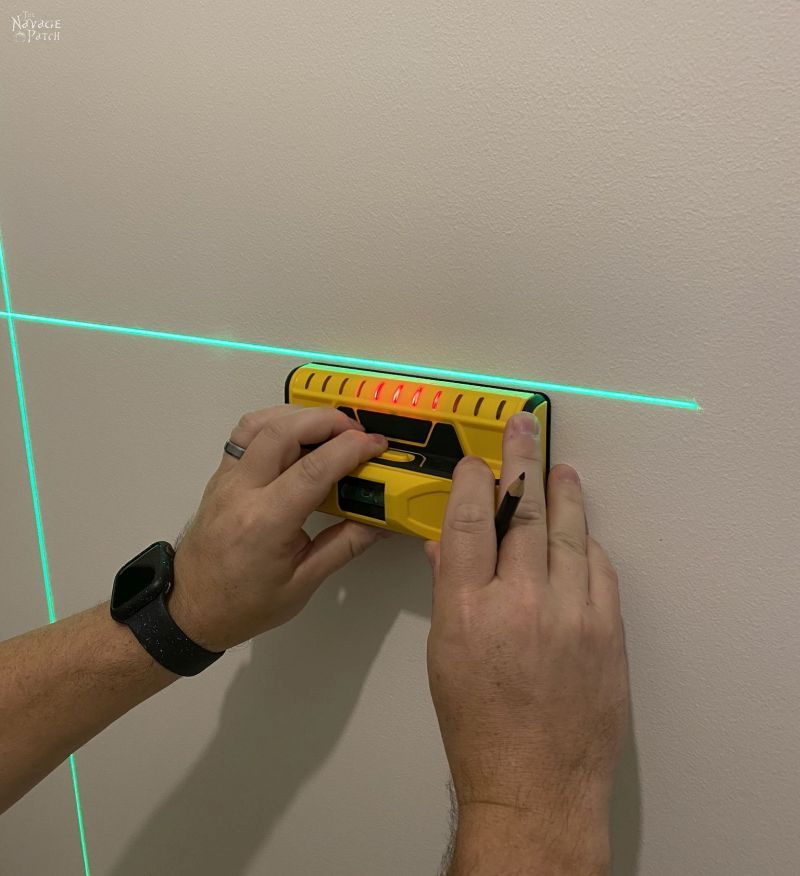 using a stud finder on a wall