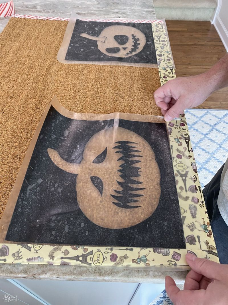 putting pumpkin stencils on a doormat