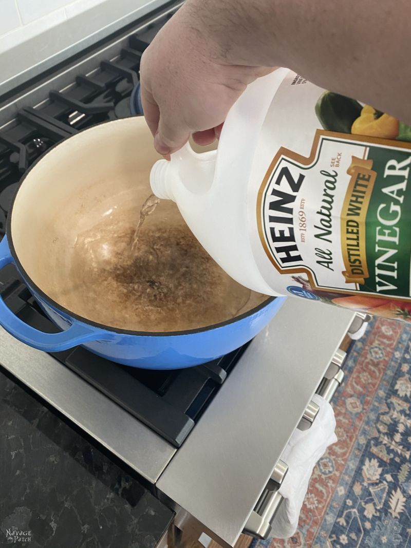 pouring vinegar into an enameled cast iron pot