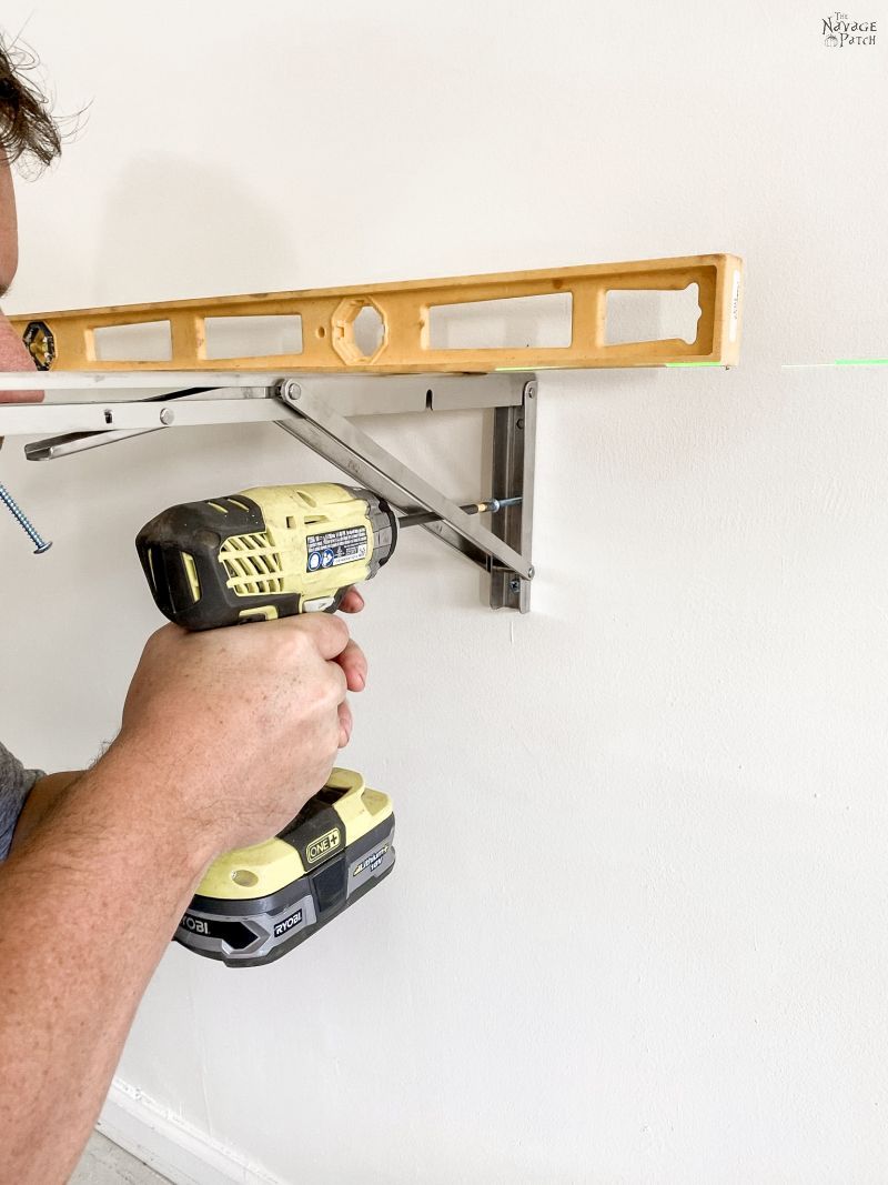 man installing a folding bracket on a garage wall