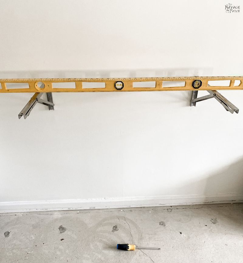 i-beam level laid across two folding brackets mounted on a wall