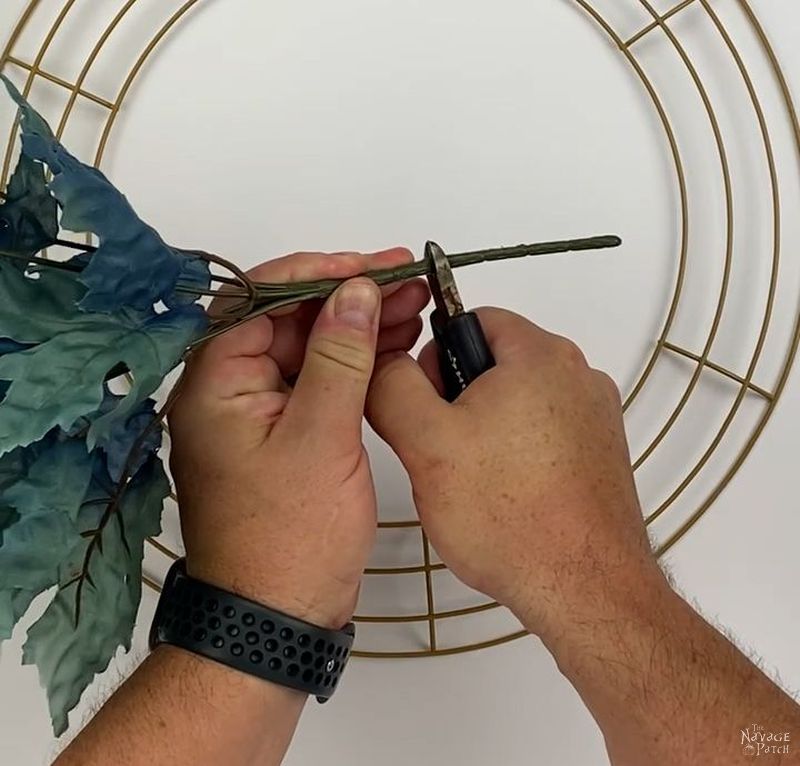 man cutting the stem of a dollar tree floral pick