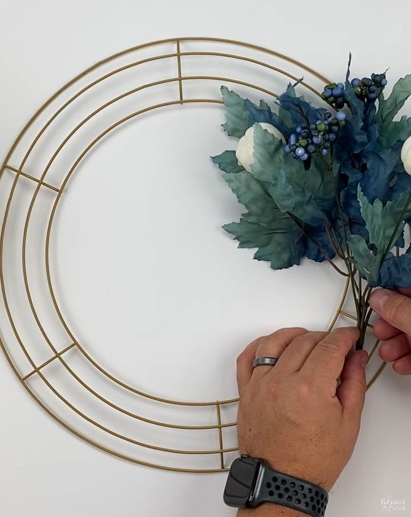 man attaching a floral pick to a wreath form