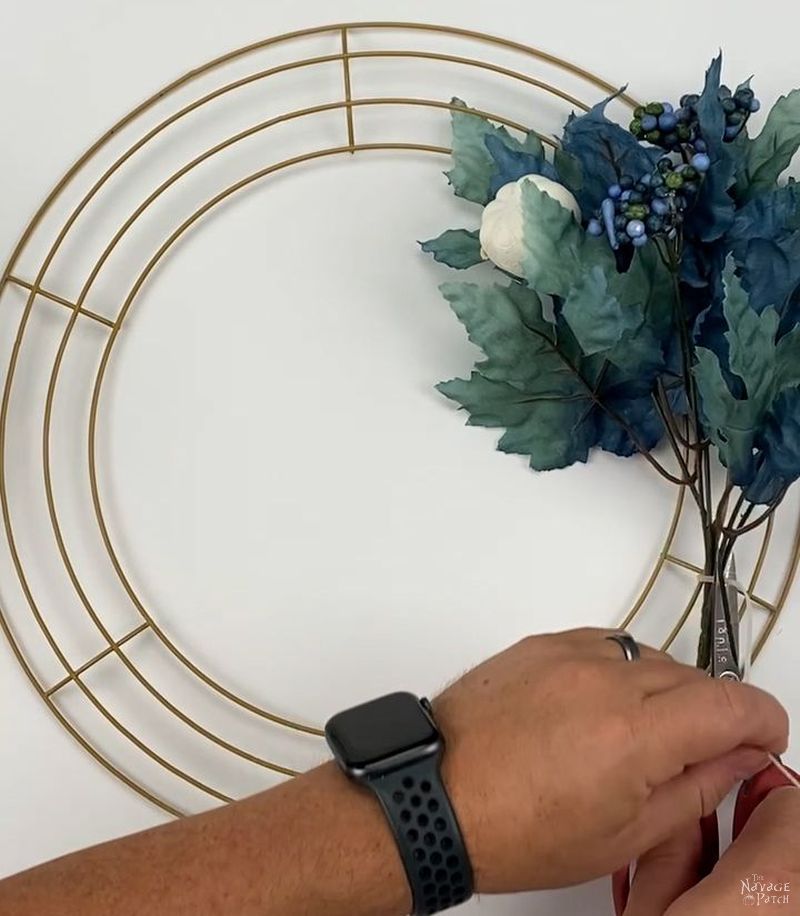 man attaching a floral pick to a wreath form