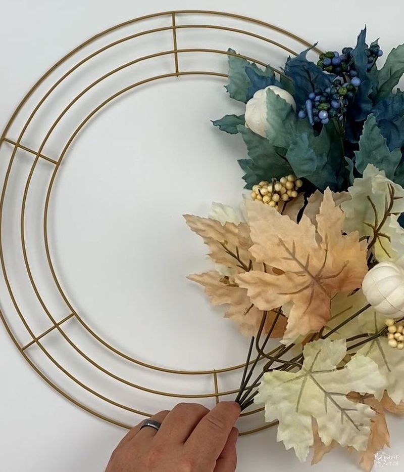 man attaching a floral pick to a wreath form