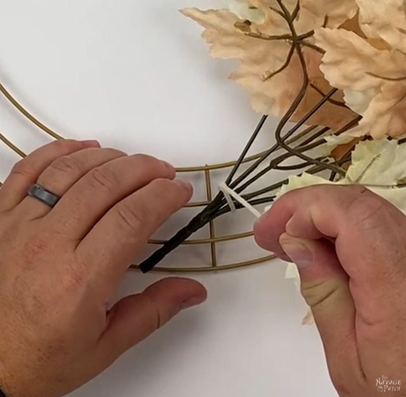 man attaching a floral pick to a wreath form