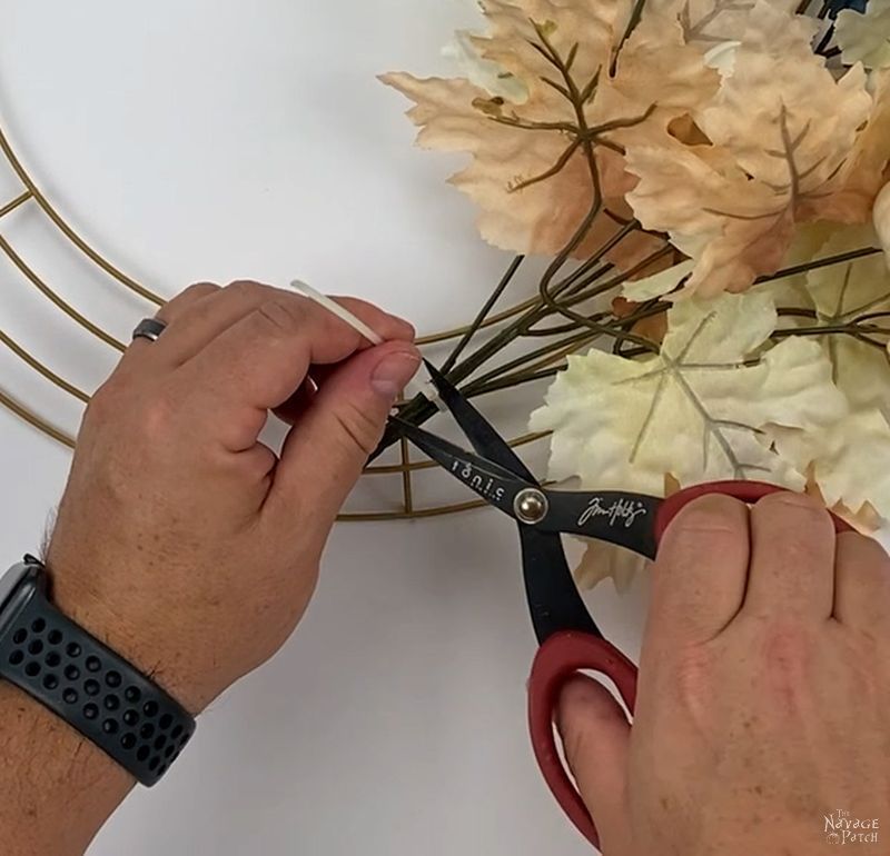 man attaching a floral pick to a wreath form
