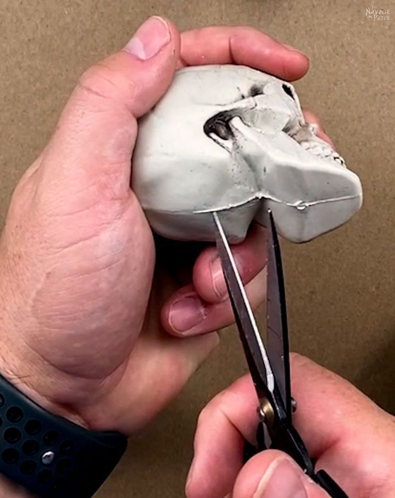 man cutting a plastic skull with scissors