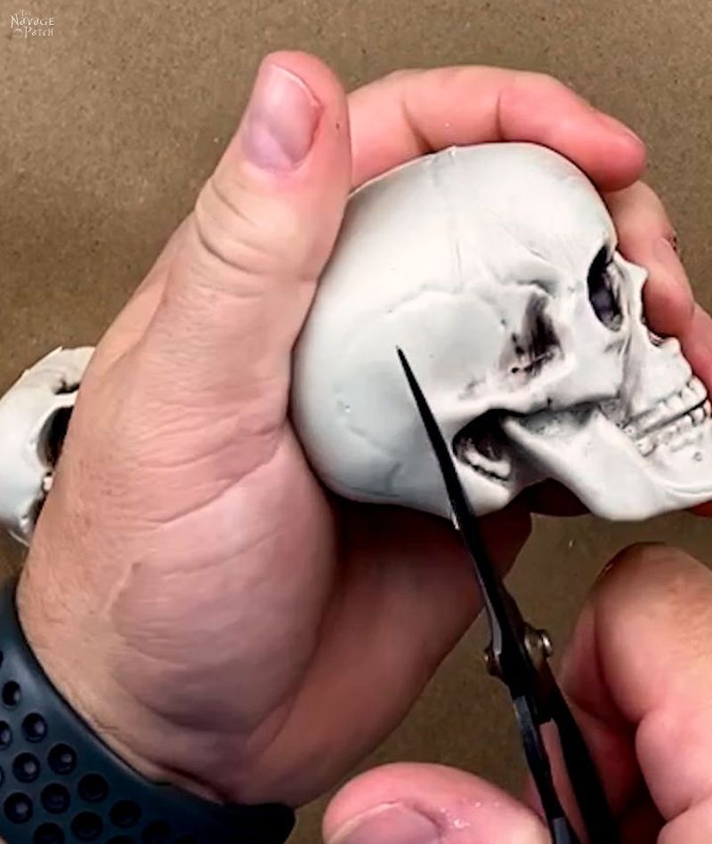 man cutting a plastic skull with scissors