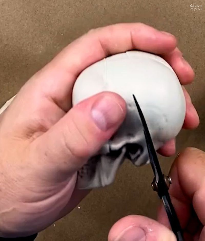 man cutting a plastic skull with scissors