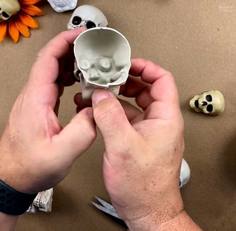 man cutting a plastic skull with scissors