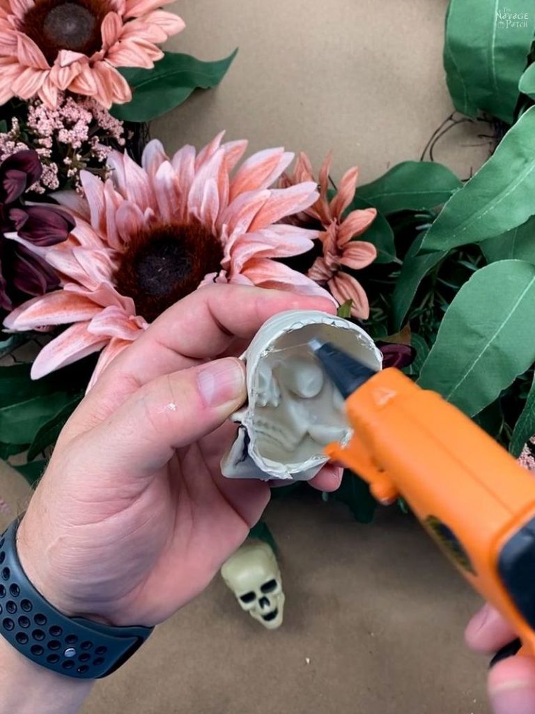 man putting hot glue on a plastic skull