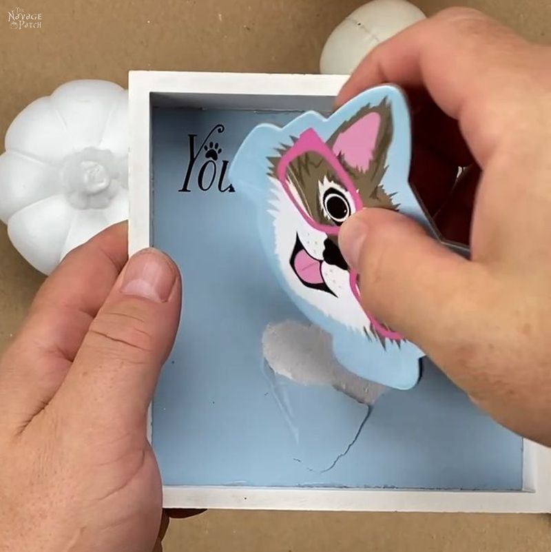 man removing a cat shape from a shadow box