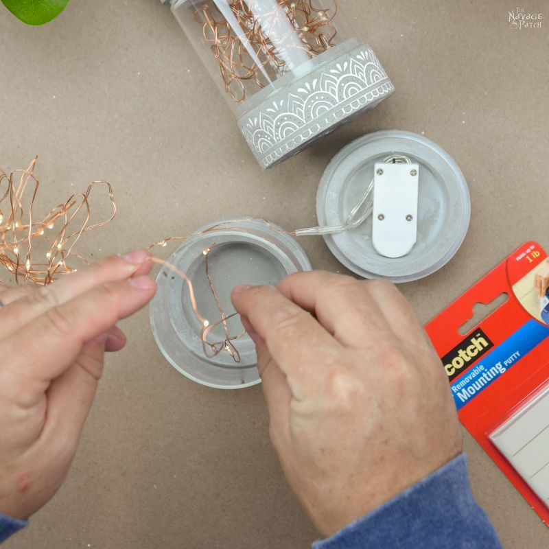 man stuffing string lights into a candle holder